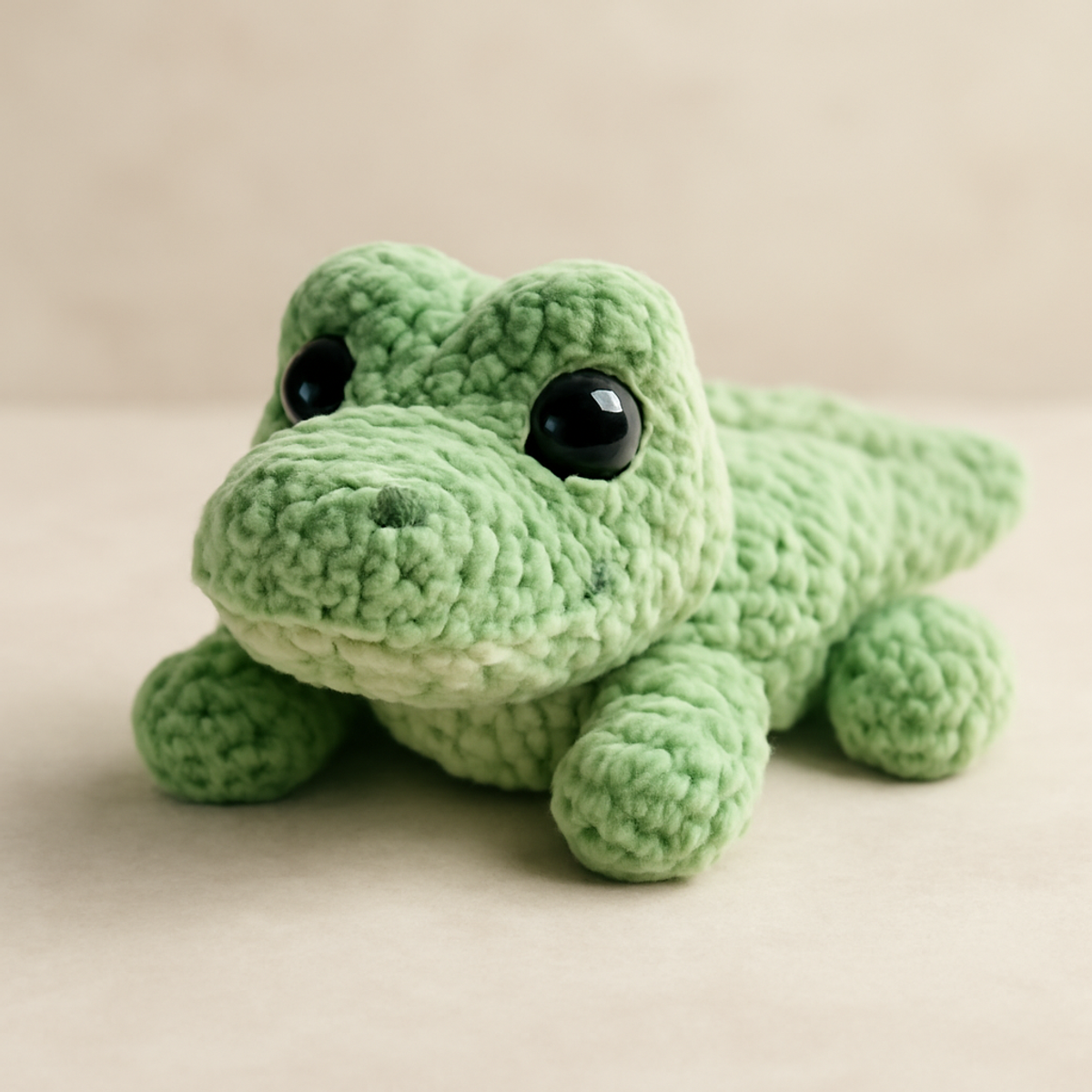 A cute green gator crochet pattern showcasing a light green plush toy with a rounded head, short limbs, and large safety eyes, made using soft chenille yarn.